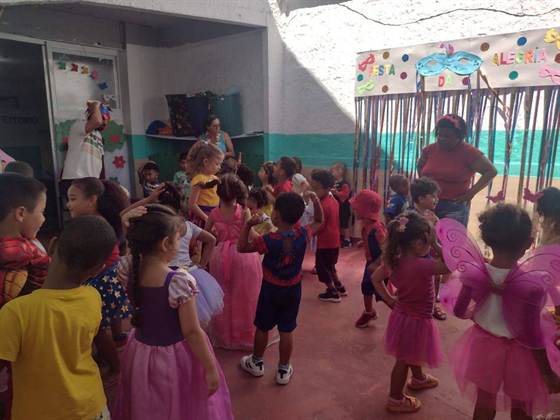 Educadora e animador brincam com as crianças fantasiadas durante o carnaval, no pátio decorado