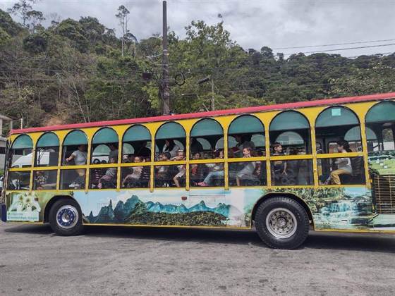 Crianças no passeio, a bordo de um bondinho turístico amarelo e vermelho