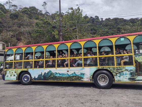 Crianças acenando pelas janelas do bondinho durante o passeio